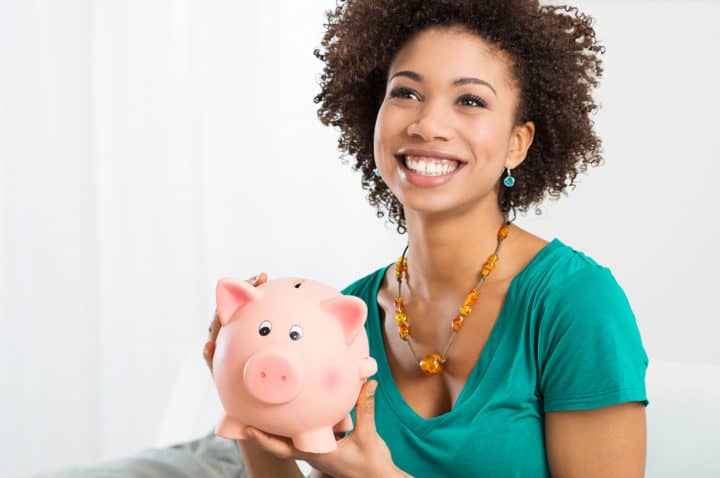 Happy Young Woman Saves Money in Piggy bank