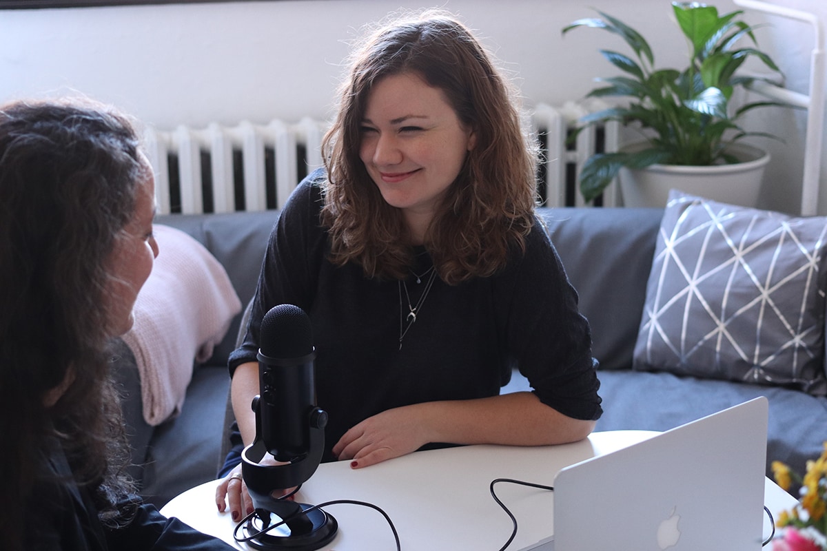 A female college student record audio with a microphone and Macbook